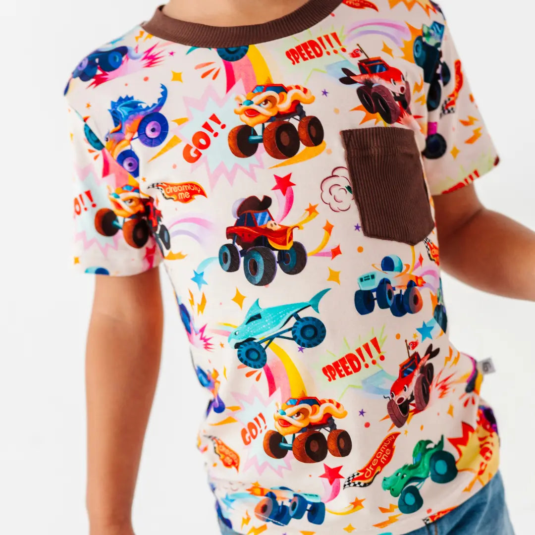 Close-up of a cream tee with a brown chest pocket and a colorful monster truck print with Go and Speed lettering.